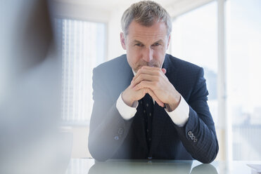 Serious older Caucasian businessman leaning on desk - BLEF03525