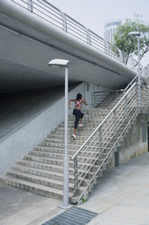 Gemischtrassige Frau läuft eine städtische Treppe hinauf - BLEF03557