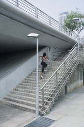 Mixed Race woman running up urban staircase - BLEF03557