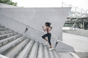 Mixed Race woman running up urban staircase - BLEF03559