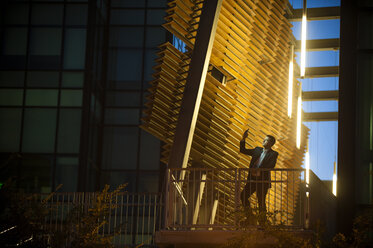 Businessman on balcony posing for cell phone selfie at night - BLEF03568