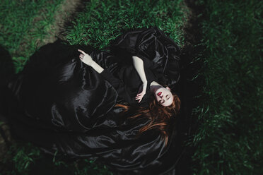 Kaukasische Frau im schwarzen Kleid schläft im Gras - BLEF03574