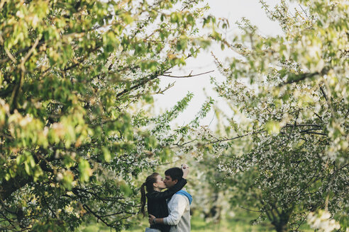 Kaukasisches Paar küsst sich in der Nähe von Bäumen - BLEF03584