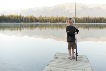 Kaukasischer Junge steht auf einem Steg am See und hält eine Angelrute - BLEF03647