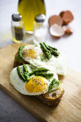 Slices of baguette garnished with fried eggs and Asparagus on a plate - GIOF06328