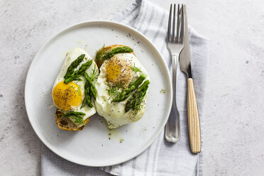 Slices of baguette garnished with fried eggs and Asparagus on a plate - GIOF06330