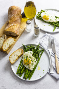 Spargel, Spiegeleier und Baguette auf Tellern - GIOF06333