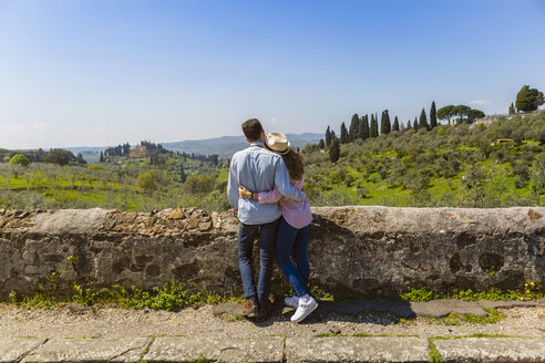 Young couple embracing at wall in Florence, Tuscany, Italy - MGIF00436