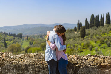 Junges Paar umarmt sich an einer Mauer in Florenz, Toskana, Italien - MGIF00440