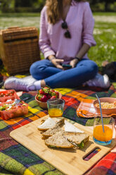 Junge Frau bei einem Picknick mit gesundem Essen in einem Park - MGIF00453