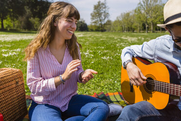 Junger Mann spielt Gitarre für seine Freundin in einem Park - MGIF00463