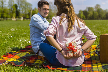 Young woman gifting her boyfriend with a present in a park - MGIF00466