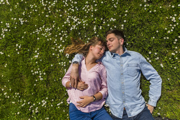 Happy young couple relaxing on grass in a park, overhead view - MGIF00476