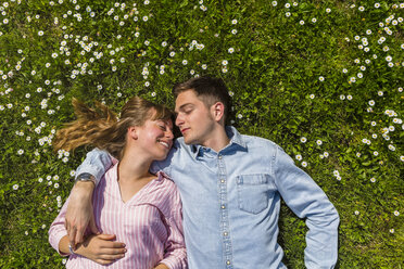 Happy young couple relaxing on grass in a park, overhead view - MGIF00477