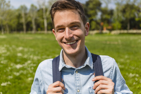 Lächelnder junger Mann in einem Park, Porträt, lizenzfreies Stockfoto