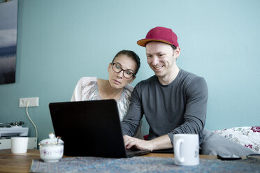 Mutter und Sohn sitzen am Küchentisch und benutzen einen Laptop - FLLF00138