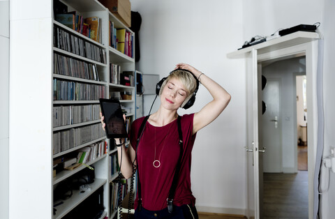 Frau hört zu Hause mit Kopfhörern Musik, lizenzfreies Stockfoto