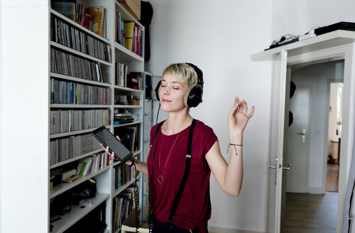 Woman listening to music with headphones at home - FLLF00148