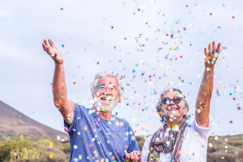 Glückliches Seniorenpaar feiert mit Konfetti im Freien - SIPF01979