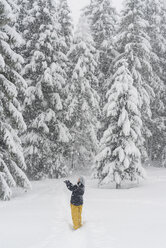 Finland, Kuopio, woman catching snowflakes in winter forest - PSIF00261