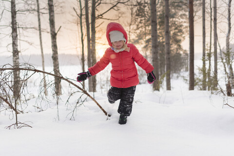 Finnland, Kuopio, glückliches Kleinkind Mädchen läuft in Winterlandschaft bei Sonnenuntergang, lizenzfreies Stockfoto