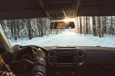 Finnland, Kuopio, Frau fährt Auto in Winterlandschaft bei Sonnenuntergang - PSIF00268