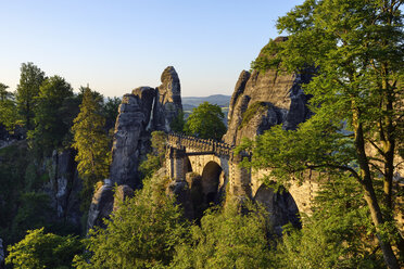 Deutschland, Sachsen, Elbsandsteingebirge, Blick auf die Bastei-Felsformation bei Sonnenaufgang mit Basteibrücke - RUEF02196