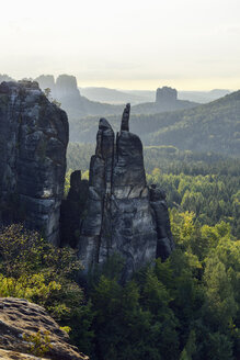 Deutschland, Sachsen, Elbsandsteingebirge, Sandsteinfelsen Brosinnadel mit Falkenstein und Schrammsteinen im Hintergrund - RUEF02225