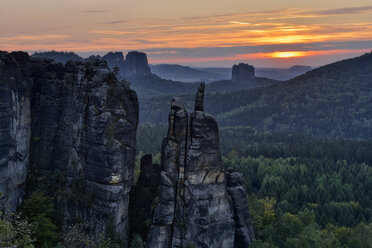 Deutschland, Sachsen, Elbsandsteingebirge, Sandsteinfelsen Brosinnadel mit Falkenstein und Schrammsteinen im Hintergrund bei Sonnenuntergang - RUEF02226