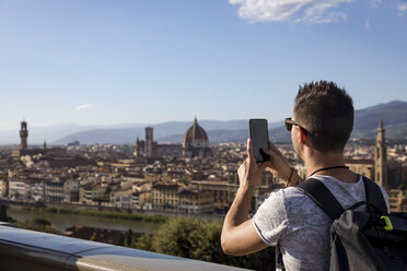 Man taking a photo of Florence with his smartphone, Florence, Italy - MAUF02454