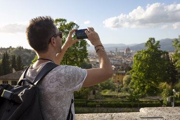 Man taking a photo of Florence with his smartphone, Florence, Italy - MAUF02459