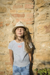 Mädchen mit Strohhut, das mit geschlossenen Augen an der Wand lehnt, Toskana, Italien - OJF00340