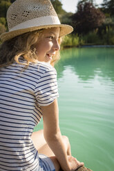 Mädchen mit Strohhut am Swimmingpool sitzend, Toskana, Italien - OJF00343