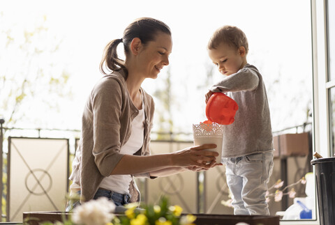 Mother and daughter planting flowers together on balcony stock photo