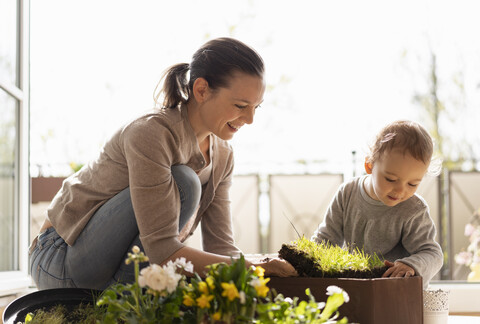 Mutter und Tochter pflanzen gemeinsam Blumen auf dem Balkon, lizenzfreies Stockfoto