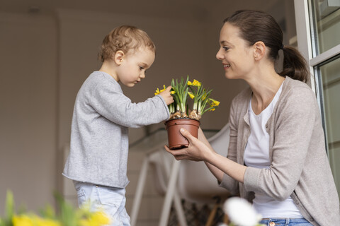 Niedliches kleines Mädchen, das eine von ihrer Mutter gehaltene Blume untersucht, lizenzfreies Stockfoto