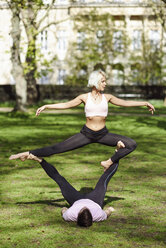 Young couple doing yoga acrobatics in an urban park - JSMF01078