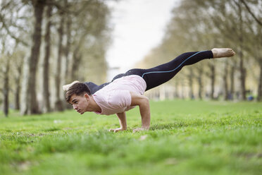 Junger Mann macht gymnastische Akrobatik in einem Stadtpark - JSMF01085