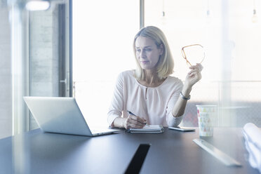 Businesswoman using laptop in office - UUF17493