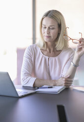 Businesswoman using laptop in office - UUF17528