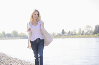 Happy mature woman walking at the riverside - UUF17540