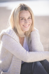 Portrait of smiling mature woman sitting outdoors - UUF17559