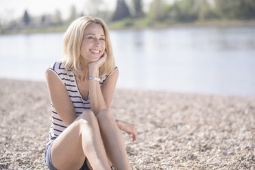 Smiling mature woman sitting at the riverside - UUF17593