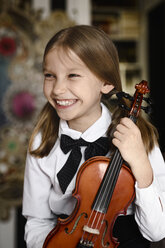 Porträt eines glücklichen Mädchens mit einer Geige zu Hause - EYAF00221