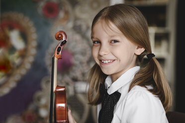 Porträt eines lächelnden Mädchens mit einer Geige zu Hause - EYAF00223
