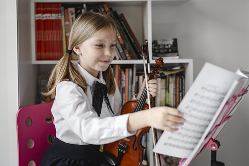 Lächelndes Mädchen mit Geige betrachtet die Noten auf dem Notenständer - EYAF00230