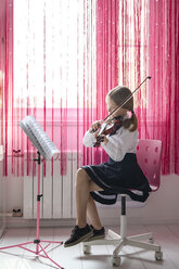 Mädchen sitzt am Fenster zu Hause und spielt Geige - EYAF00232