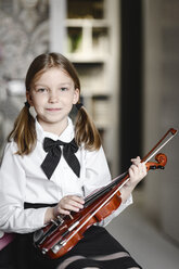 Porträt eines lächelnden Mädchens mit einer Geige zu Hause - EYAF00235