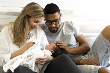 Happy father and mother with their newborn baby in bed - ERRF01307