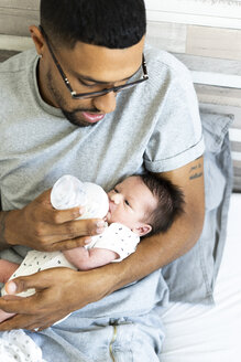 Vater füttert sein neugeborenes Baby im Bett mit der Flasche - ERRF01313